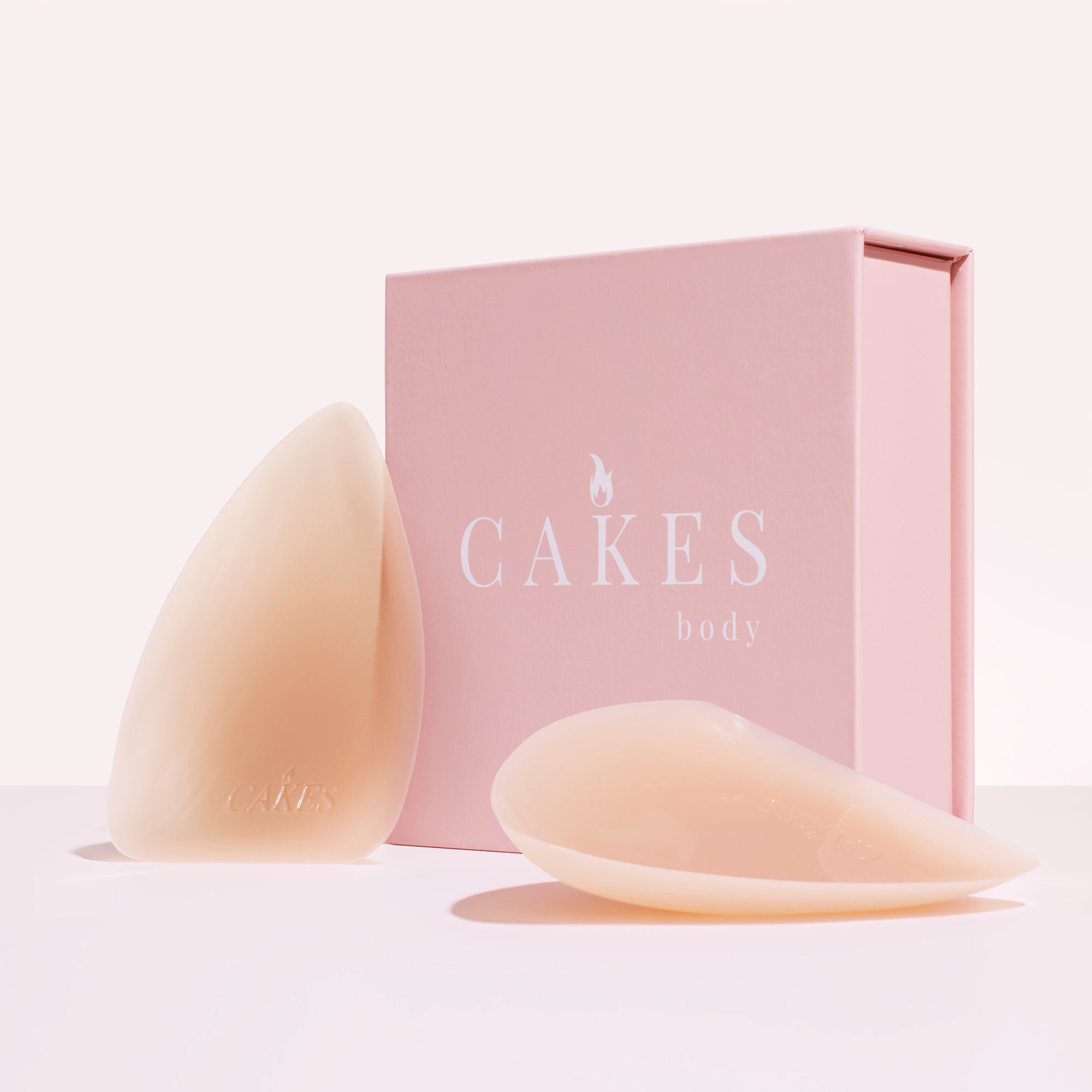 Silicone breast inserts next to a pink box labeled 'CAKES body.'